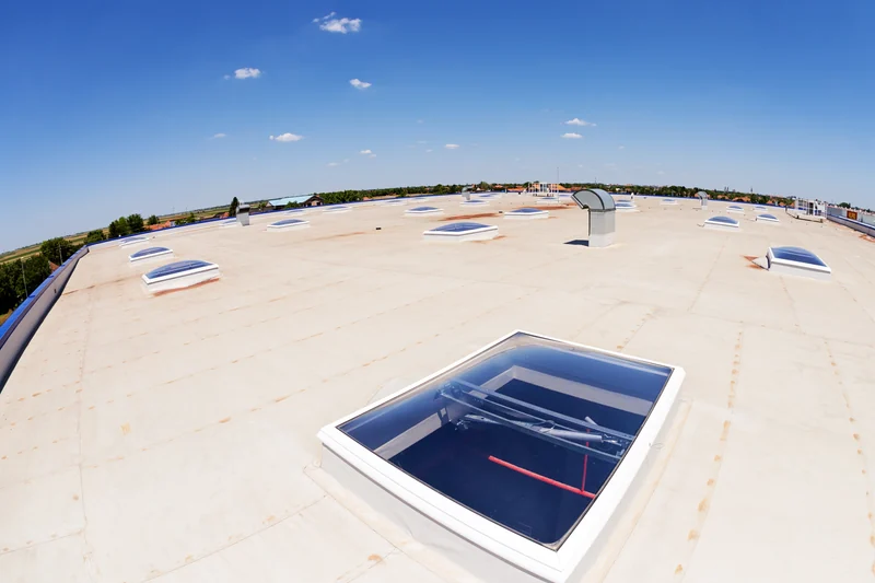 Commercial flat roof with skylights beneath a blue sky
