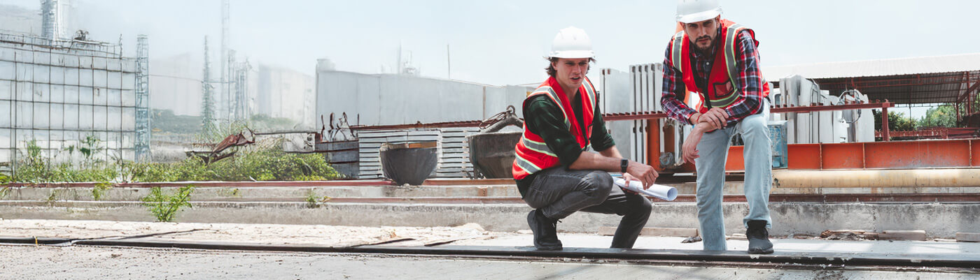 Two workers reviewing plans on a flat commercial roof