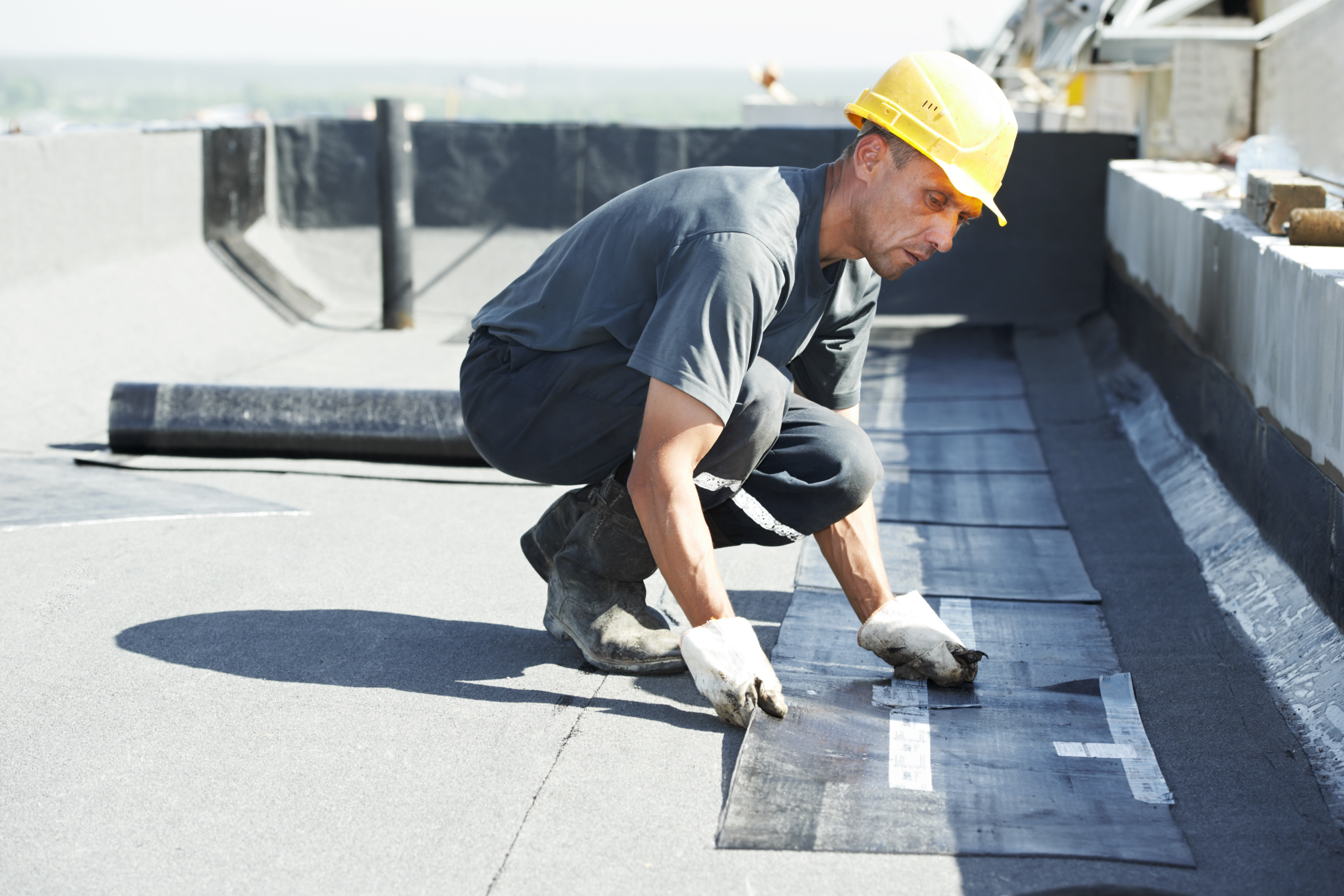 Roofer installing membrane on a commercial flat roof